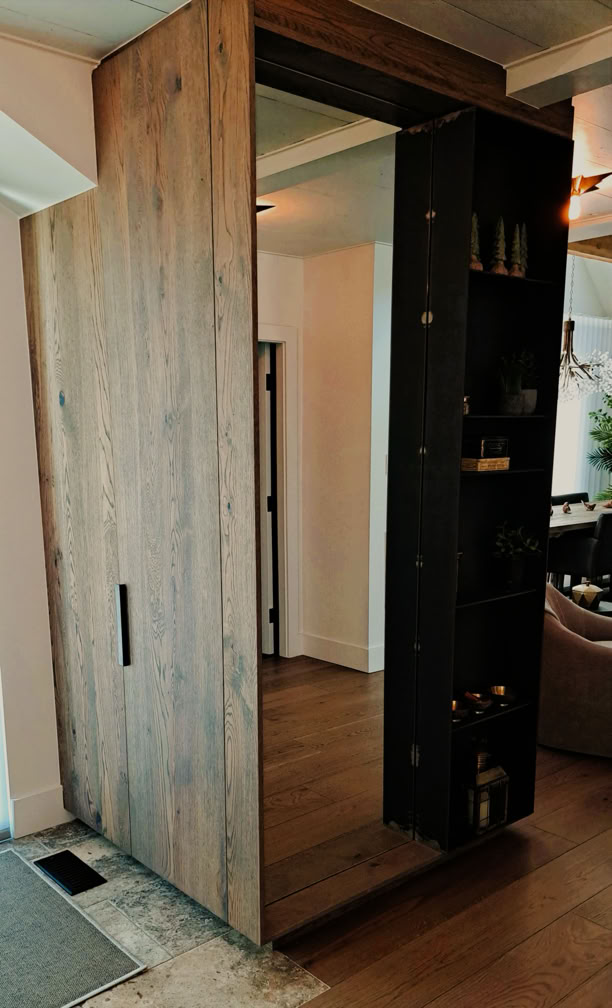 Wooden sliding door with a built-in shelf, partially open to reveal a room with wooden flooring.
